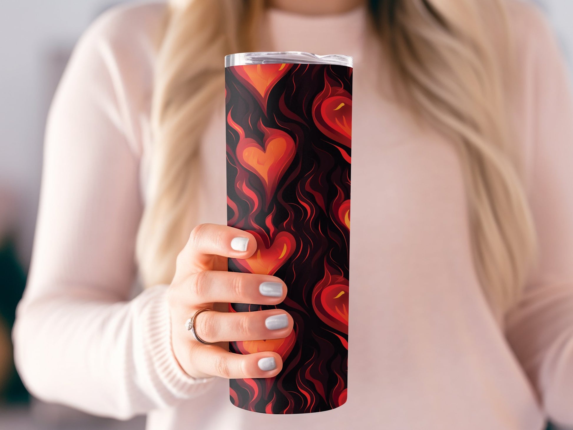 Model holding flaming hearts tumbler, slim 20oz shape with metal straw and unique heart graphic
