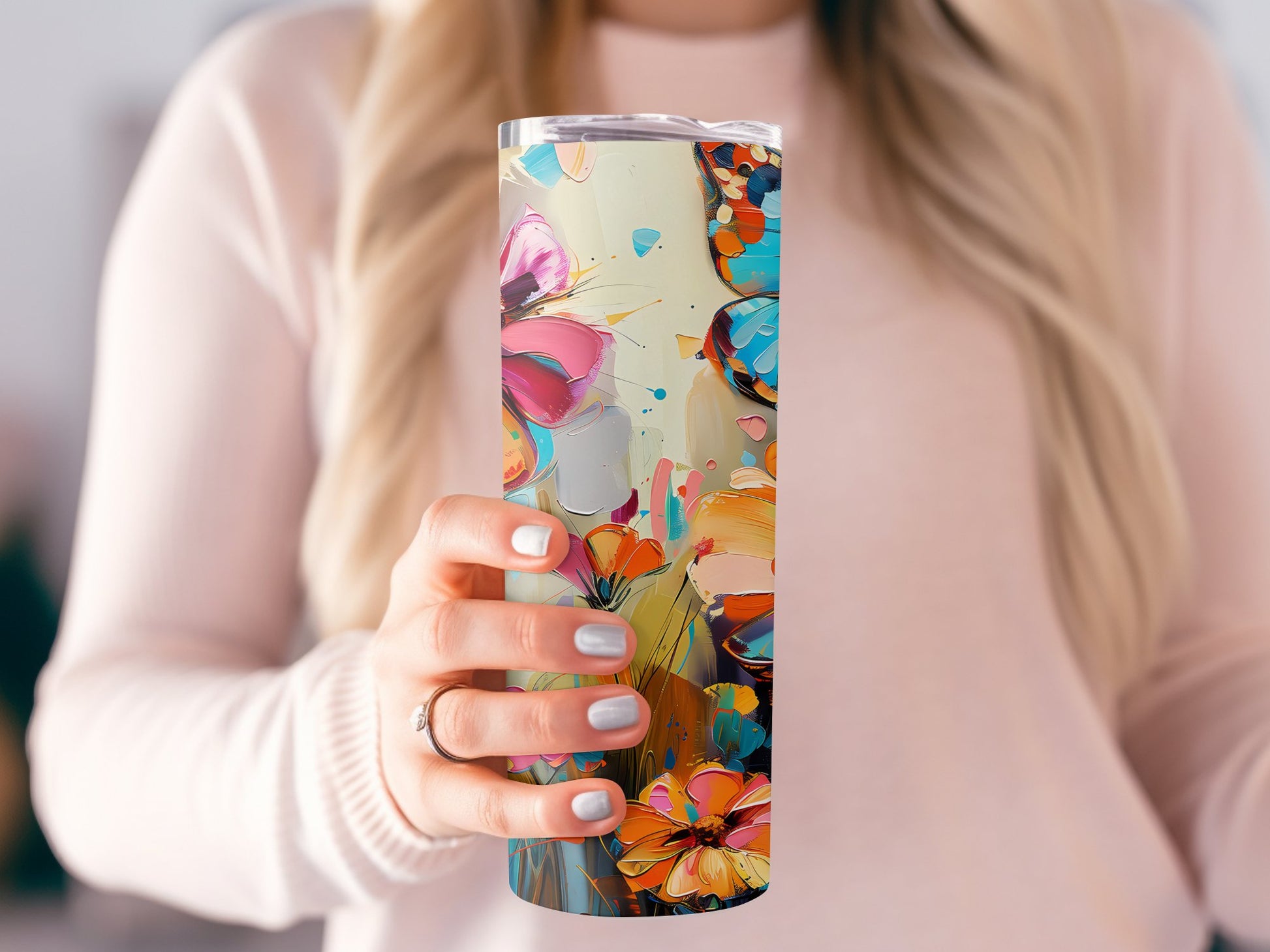 Model holding floral butterfly tumbler, slim 20oz shape with metal straw and vibrant floral print