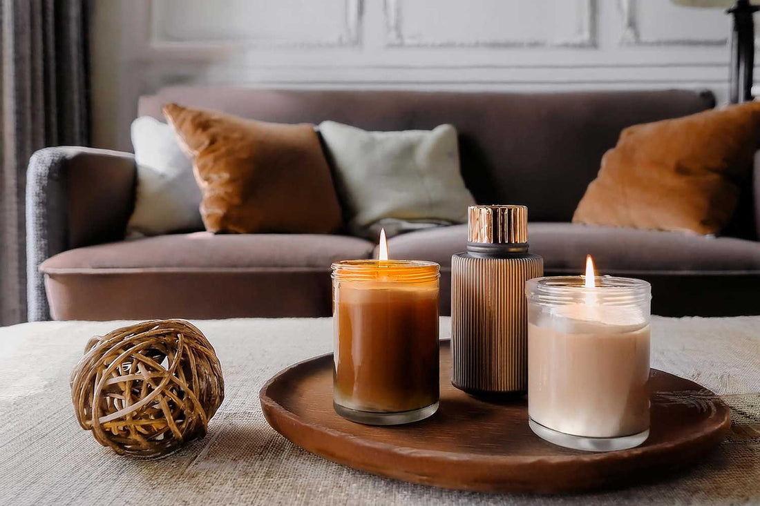 Lit scented candles arranged on a wooden tray atop a coffee table in a cosy living room.