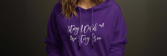 Woman wearing a royal purple hoodie with Stay Wild Stay Free white script and butterfly chest graphic.