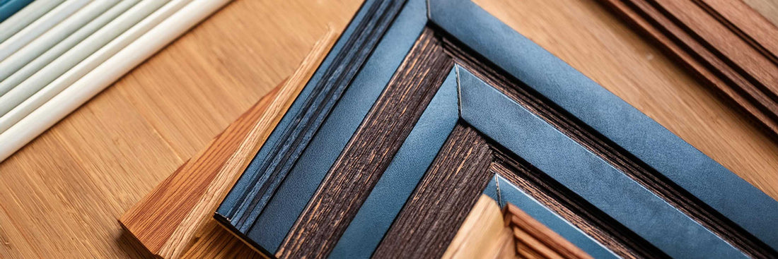 Close-up of frame corner samples and framing materials arranged on a wooden surface.