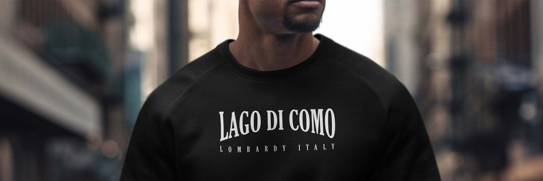 Man wearing a black crew-neck sweatshirt with Lago Di Como Lombardy Italy white chest graphic.