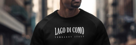 Man wearing a black crew-neck sweatshirt with Lago Di Como Lombardy Italy white chest graphic.