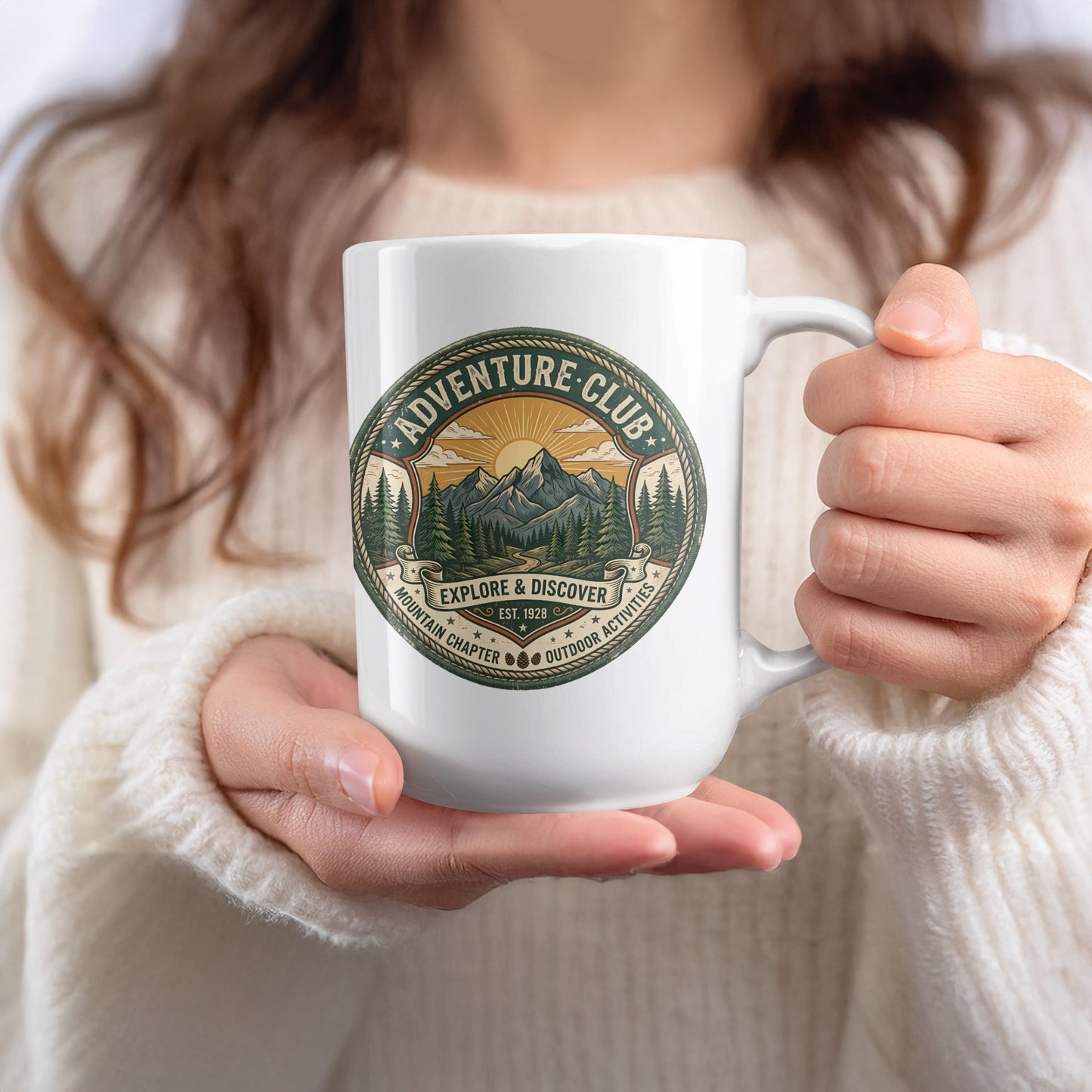 Lady holding Adventure Club 15oz ceramic mug with heritage mountain emblem and pine cone details with star accents.