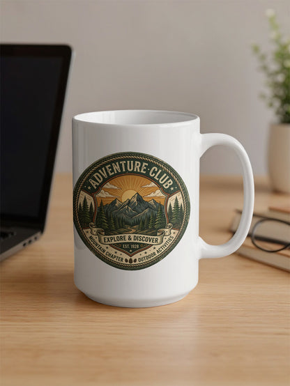 Adventure Club 15oz mug on office desk featuring twin mountains, forest trail and vintage outdoor circular badge.