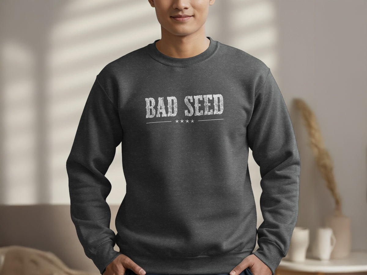 Dark Heather Grey Bad Seed Sweatshirt featuring worn white block serif lettering with cracked texture and a vintage graphic finish across the chest.