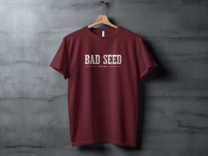 Maroon Bad Seed T-Shirt showing distressed white Bad Seed lettering with vintage texture, horizontal divider and star accents.