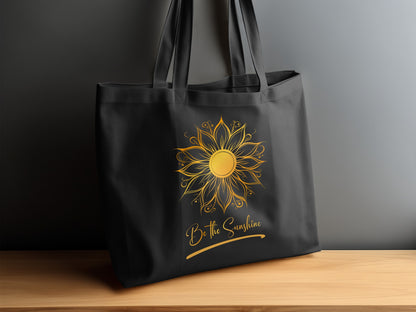 Be The Sunshine canvas tote bag on timber sideboard with detailed golden sun motif, Be the Sunshine script and brushstroke underline.