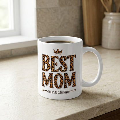 Best Mom The Real Superhero 11oz mug on kitchen counter, a stylish leopard print gift for everyday coffee rituals.