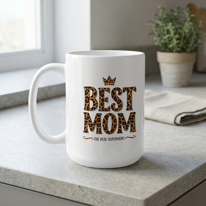 Best Mom The Real Superhero 15oz ceramic mug by window light, perfect for relaxing coffee and stylish gifting moments.