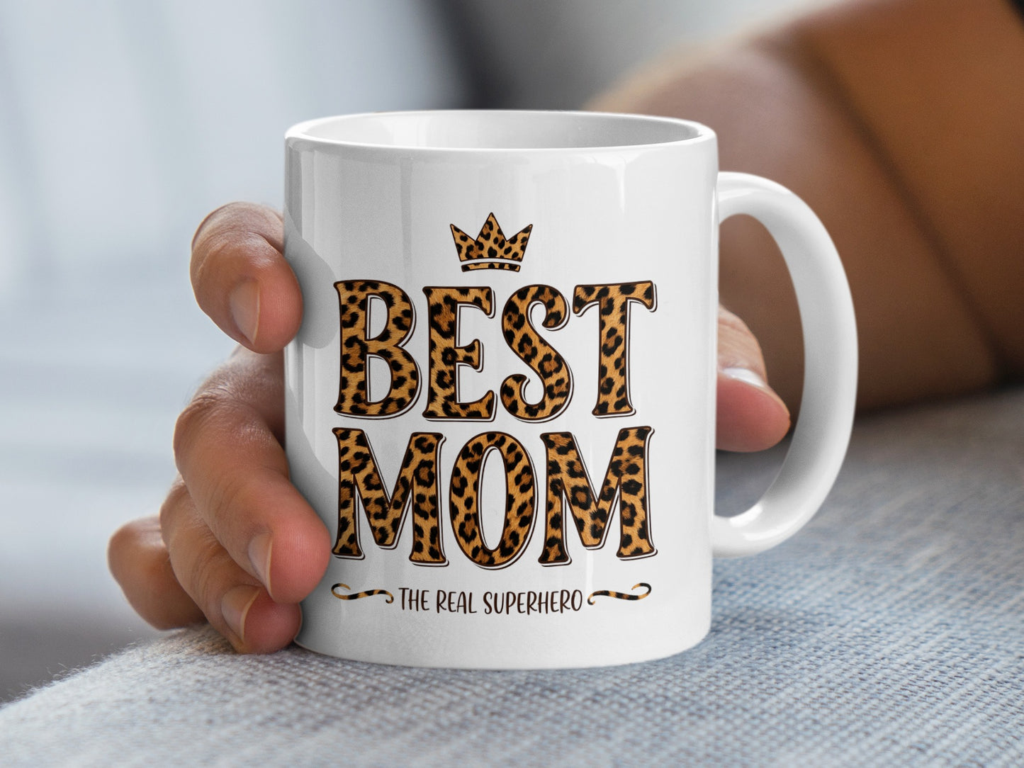 Hand holding Best Mom The Real Superhero mug with leopard print, perfect for daily coffee and heartfelt gifting.