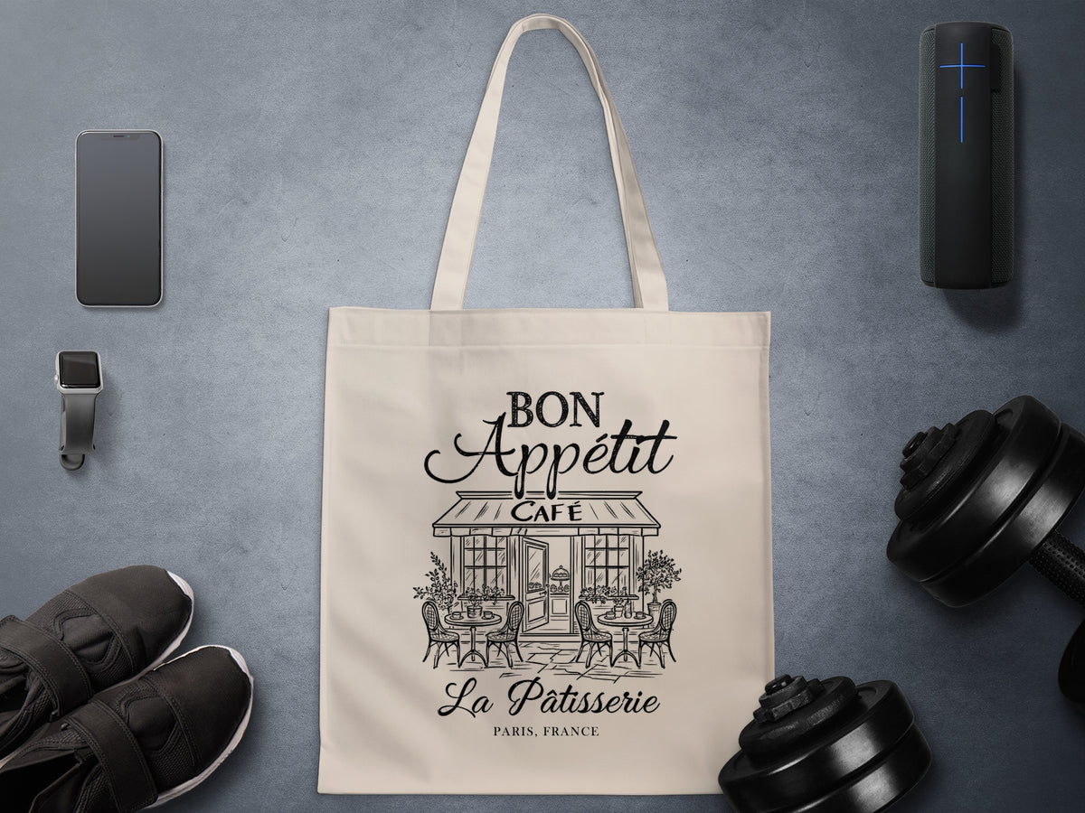 Bon Appétit La Pâtisserie canvas tote bag showing artwork with flowing script, intricate café architecture and classic Parisian street scene details.