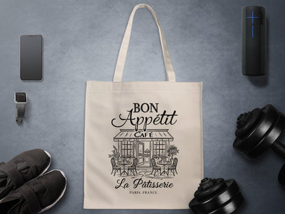 Bon Appétit La Pâtisserie canvas tote bag showing artwork with flowing script, intricate café architecture and classic Parisian street scene details.