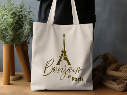 Bonjour de Paris Tote Bag featuring a tall stylised Eiffel Tower and muted olive-brown typography on natural canvas.