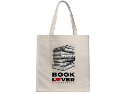 Book Lover cream canvas tote bag on white background with detailed stack of books, bold black lettering, red heart accent and small red stars.