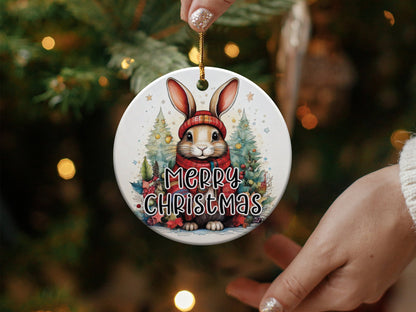 Round holiday ornament with watercolour bunny artwork, snowy evergreens, holly berries, and Merry Christmas black text.