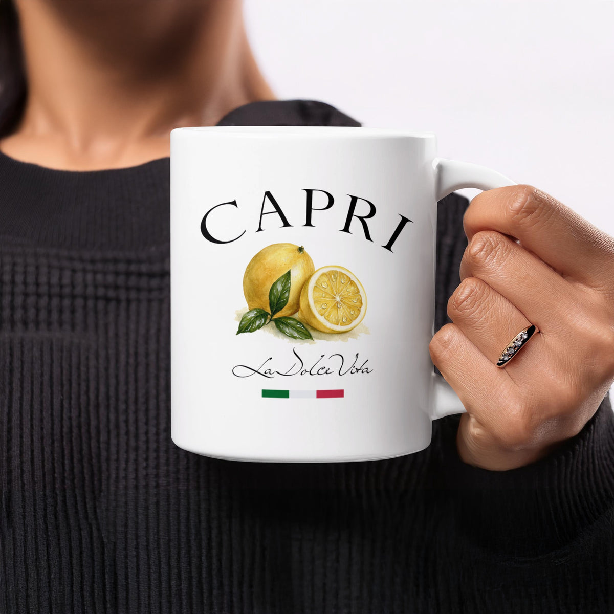 Capri 11oz lemon mug held in hand, displaying its Italian-inspired citrus illustration and classic black La Dolce Vita typography.
