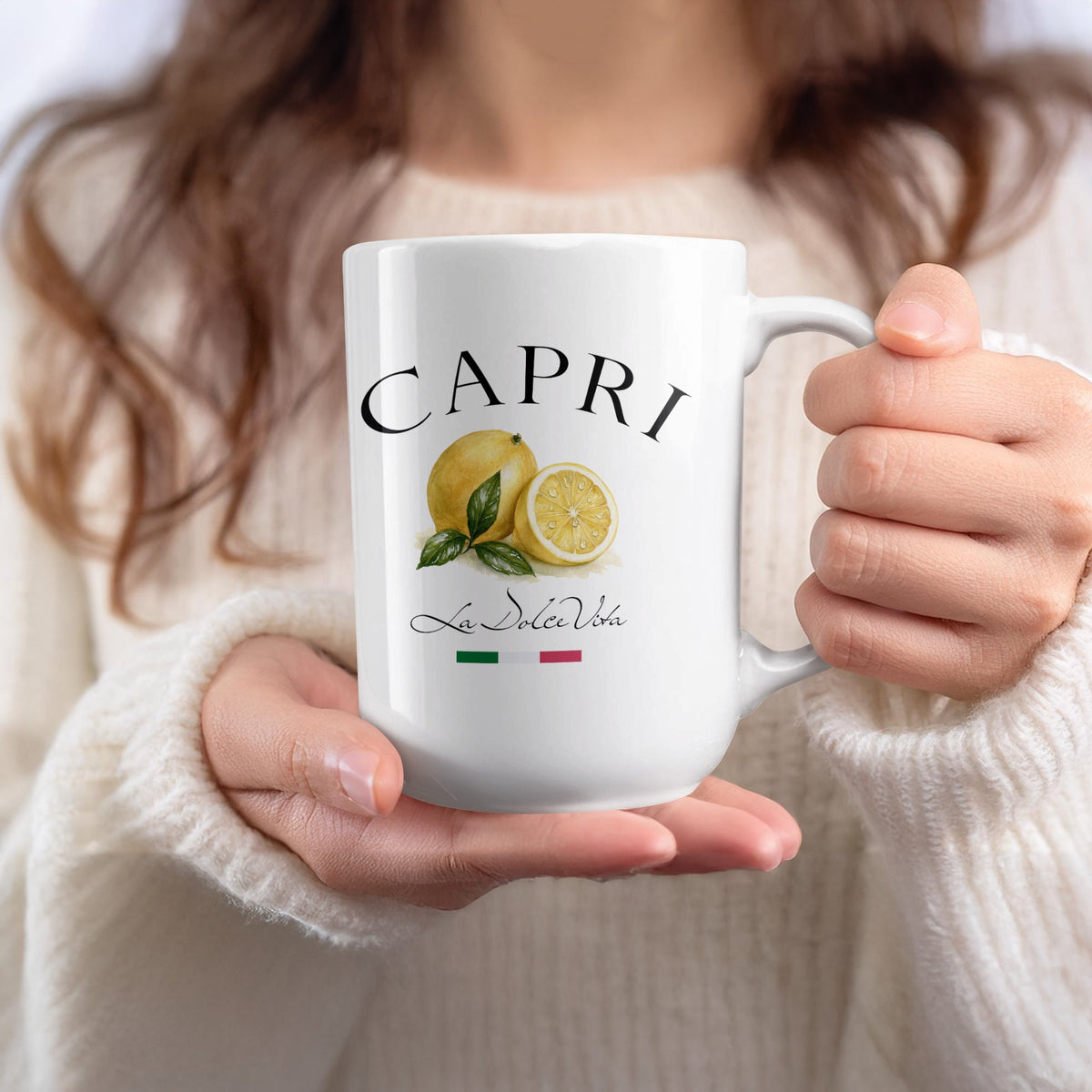 Capri 15oz lemon mug held in hand, showcasing the yellow citrus artwork, green leaves and Italian-inspired lettering.