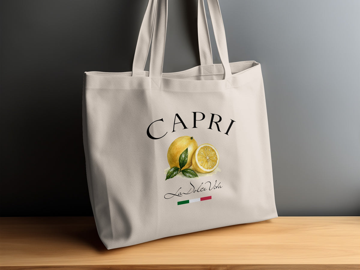 Natural canvas Capri Tote Bag displayed on a sideboard, showing the painterly lemon artwork, bold black typography and dual handles.
