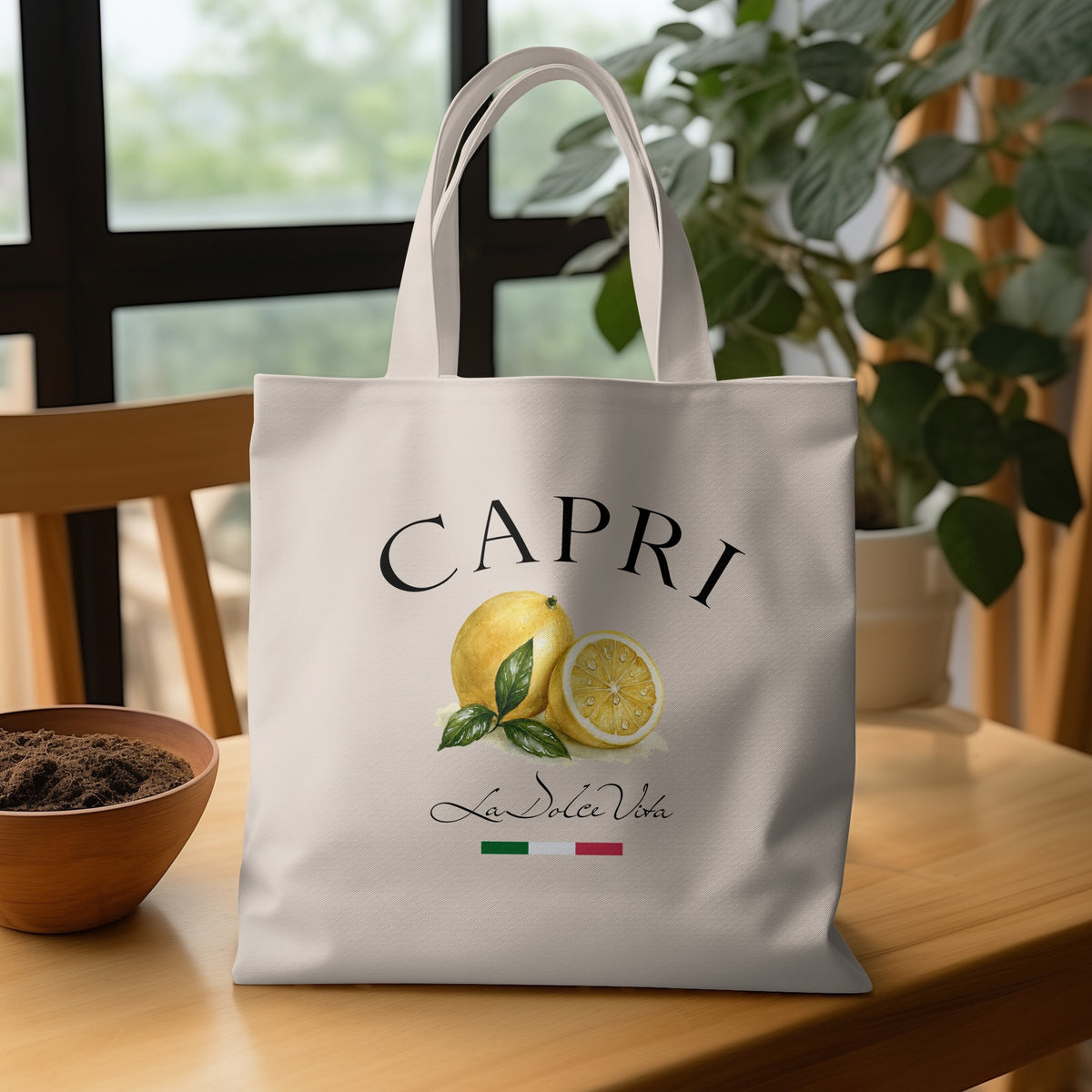 Natural-tone Capri Tote Bag on a wooden table featuring yellow lemons, green leaves, La Dolce Vita script and Italian tricolour detail.