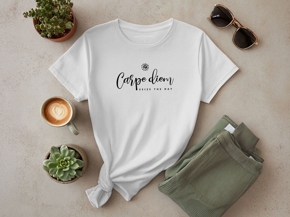 Flat lay of white crew neck t-shit featuring Carpe Diem seize the day black script graphic, styled with sage pants and coffee.