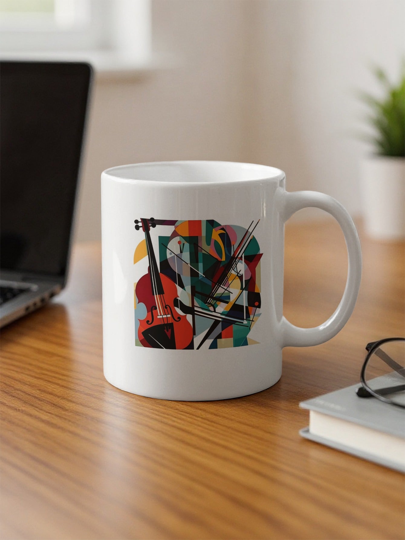 Abstract music illustration on 11oz coffee mug with cello, diagonal bow lines and bold teal, orange, yellow and purple shapes on office desk.