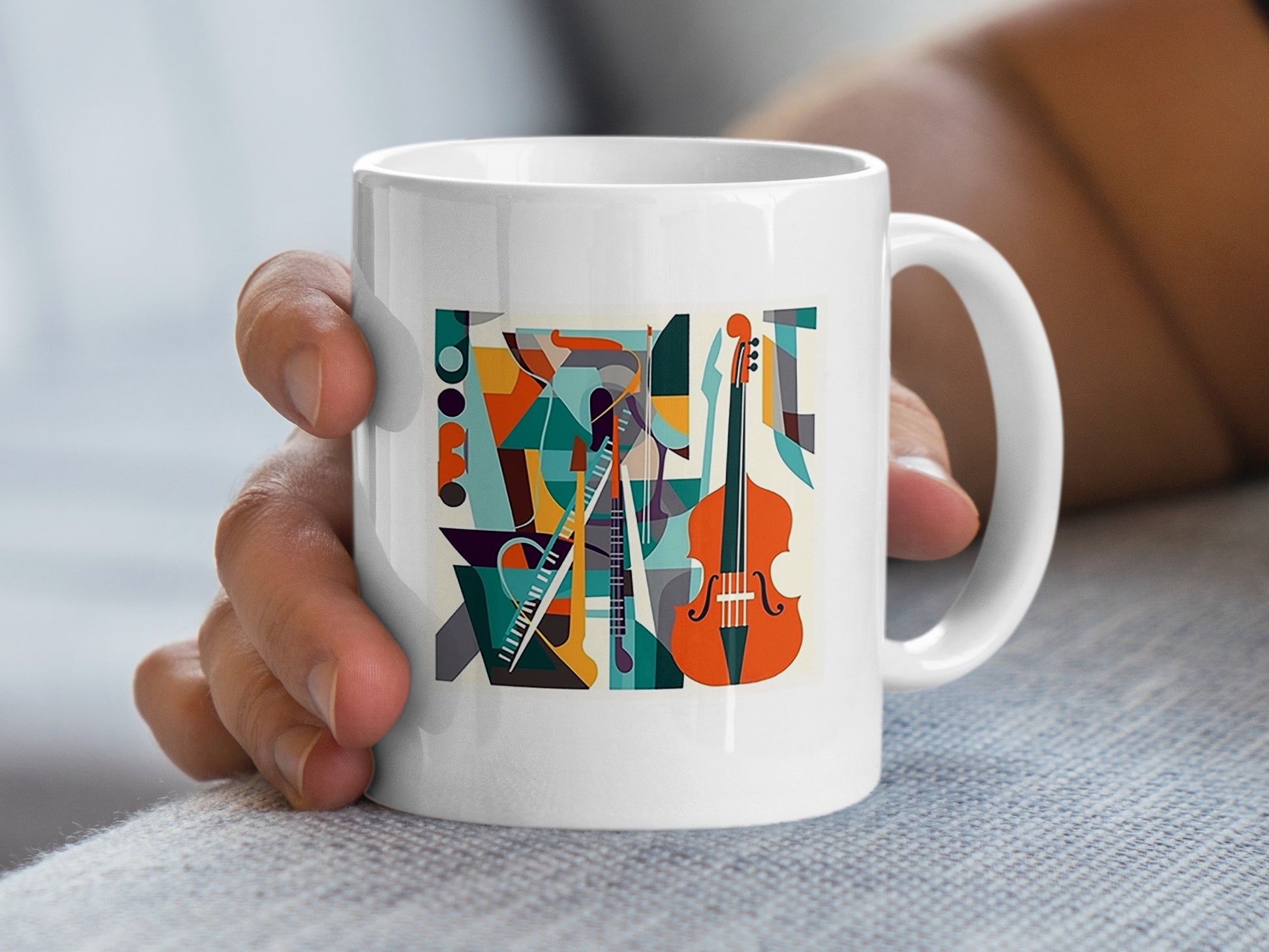 Handheld view showing modern music mug artwork with cello illustration, layered instruments and bold geometric shapes.