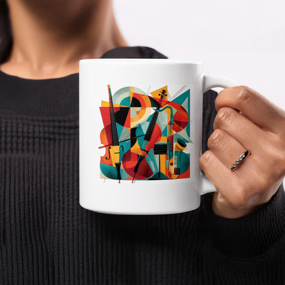 White ceramic coffee mug with abstract cello artwork featuring two instruments, overlapping circles, triangles and geometric colour blocks.