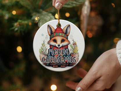 Round holiday ornament showcasing a cute woodland fox wearing festive winter clothing and Merry Christmas text.
