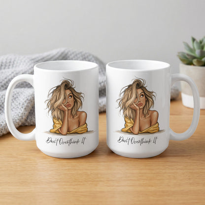 Two 15oz Don't Overthink It Mugs showing both sides with the blonde portrait, flowing black script and expressive linework.