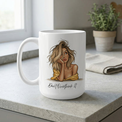 White 15oz Don't Overthink It Mug on a kitchen bench, featuring warm beige, golden and soft yellow portrait artwork.