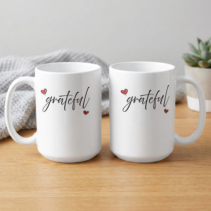 White 15oz Grateful Heart Mug showing front and reverse views with matching black script lettering and two hand-drawn red heart motifs.