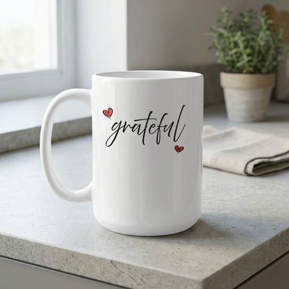 15oz Grateful Heart Mug on a kitchen bench featuring flowing handwritten black lettering and delicate red heart accents positioned diagonally.