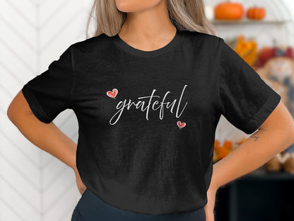 Black Grateful Heart T-Shirt with white handwritten script and two red heart accents arranged diagonally across the centre chest.