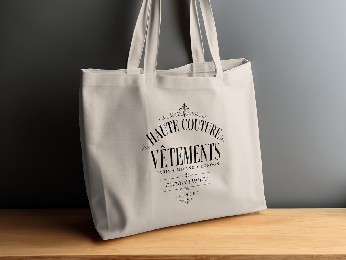 Haute Couture tote bag with black arched serif lettering, decorative scrollwork and a fleur-de-lis-style ornament.