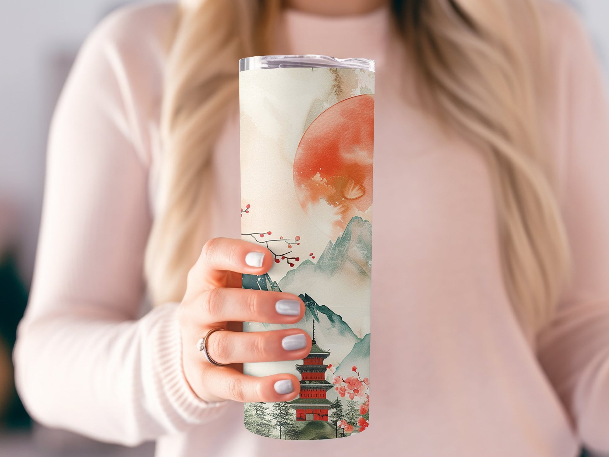 Model holding Japanese sunset tumbler, slim 20oz design with metal straw and beautiful sunset artwork