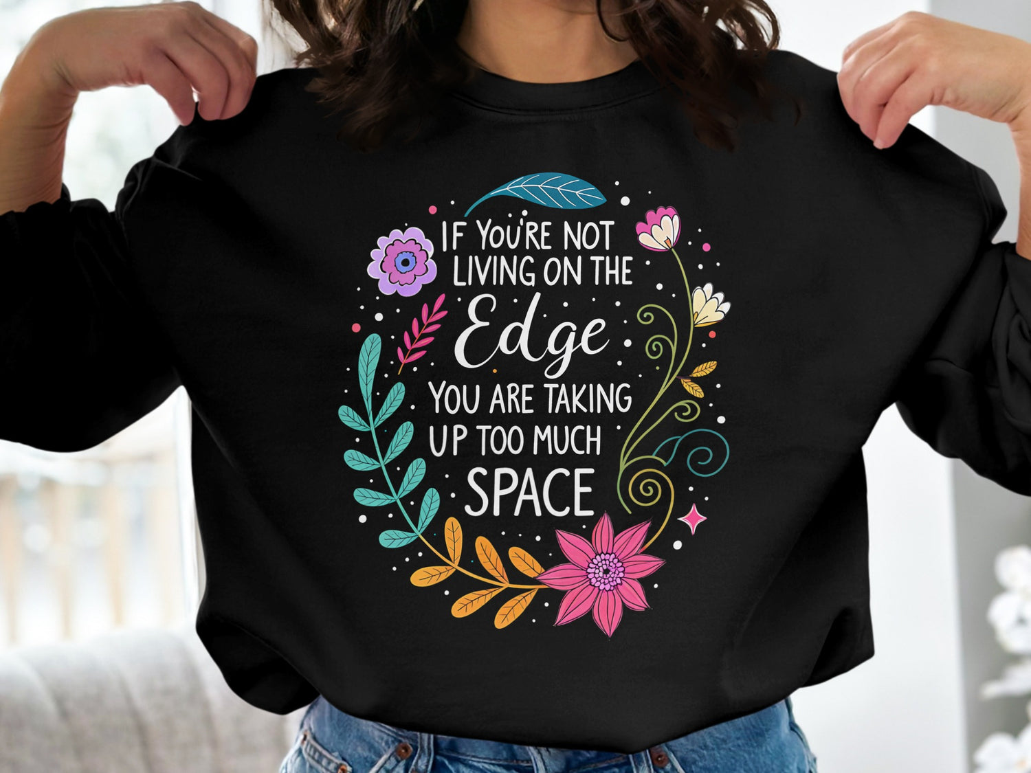 Black Live On The Edge sweatshirt with colourful floral wreath framing quote typography, centred chest print.