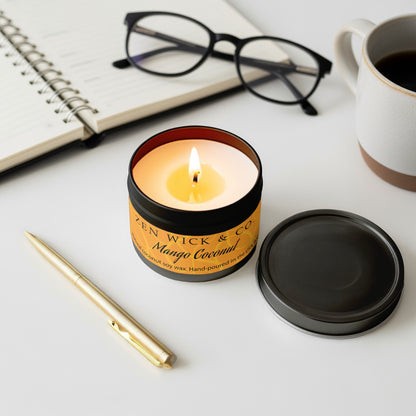 Mango coconut scented candle 4oz lit with surrounding decor creating a fresh and uplifting tropical setting.
