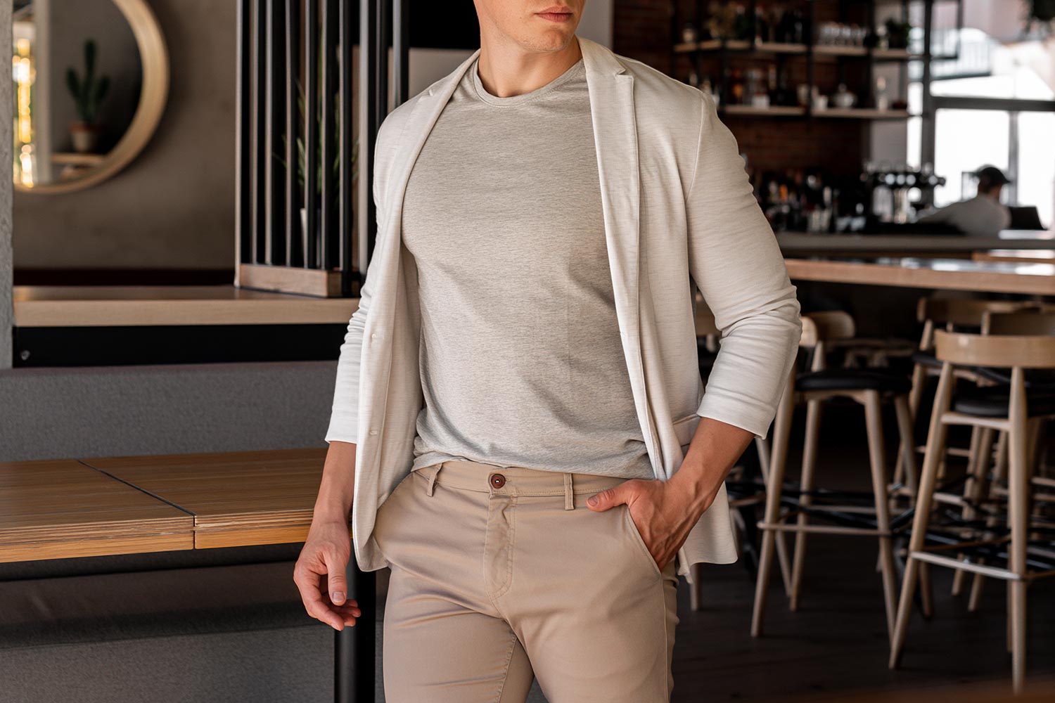 Man wearing a grey crew neck t-shirt under an open cream blazer and beige chinos for a relaxed smart casual look.