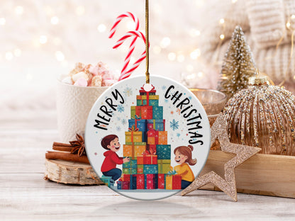 Merry Christmas ornament featuring two children stacking colourful presents beneath festive holiday lettering.