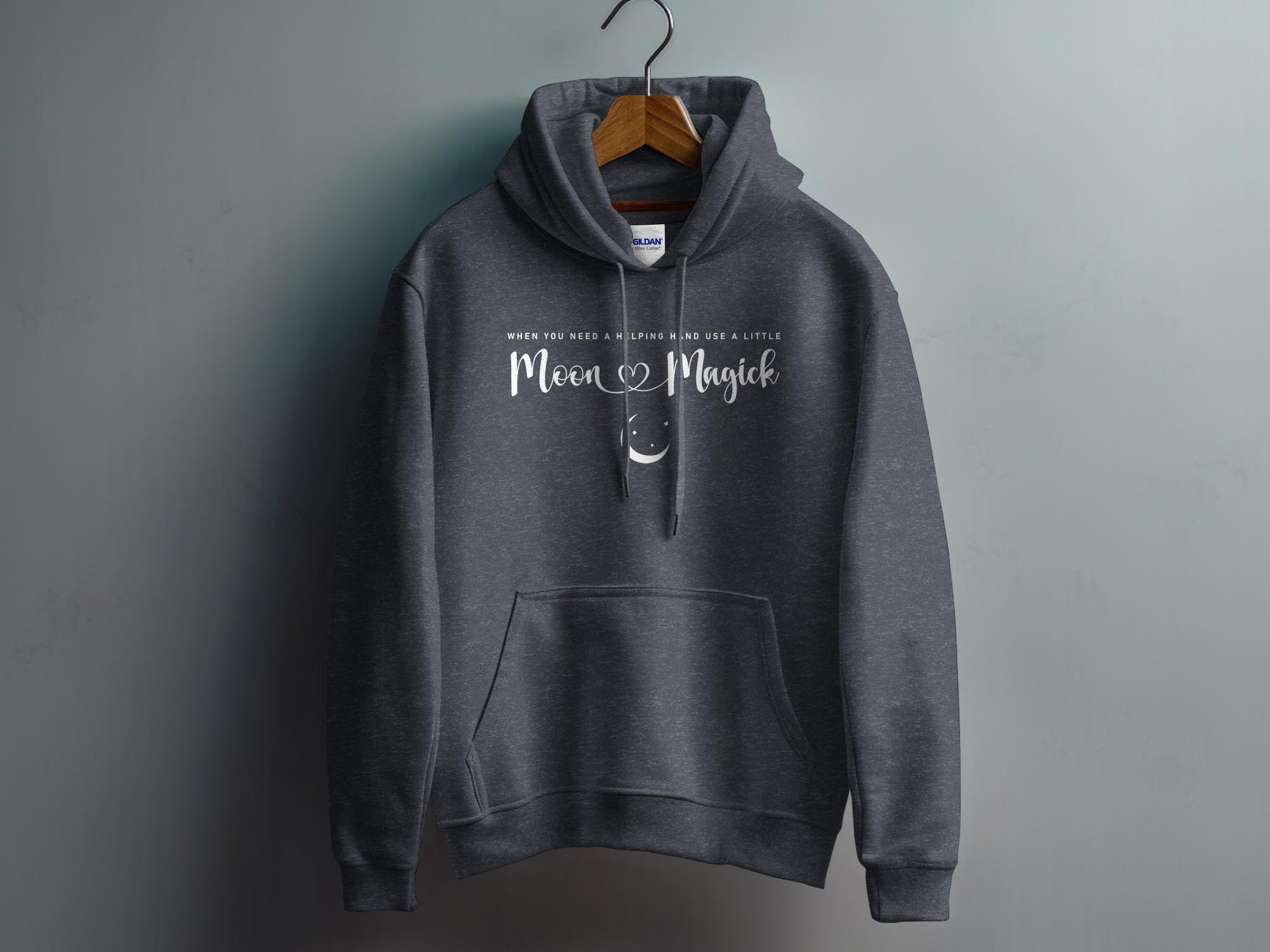 Dark Heather Grey Moon Magick Hoodie with elegant Moon Magick script lettering and small crescent moon illustration in a balanced chest design.