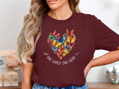 Maroon One World One Heart t-shirt with bold butterfly heart chest illustration in layered colour tones and uplifting script typography.