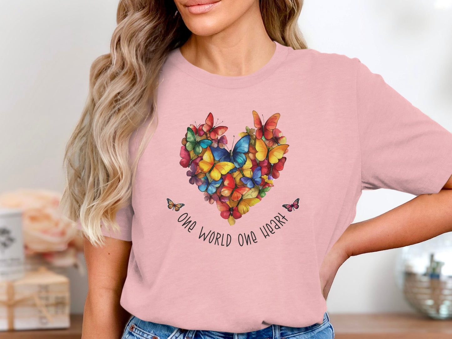 Pink One World One Heart T-shirt featuring vibrant butterfly heart design across chest with handwritten One World One Heart detail.