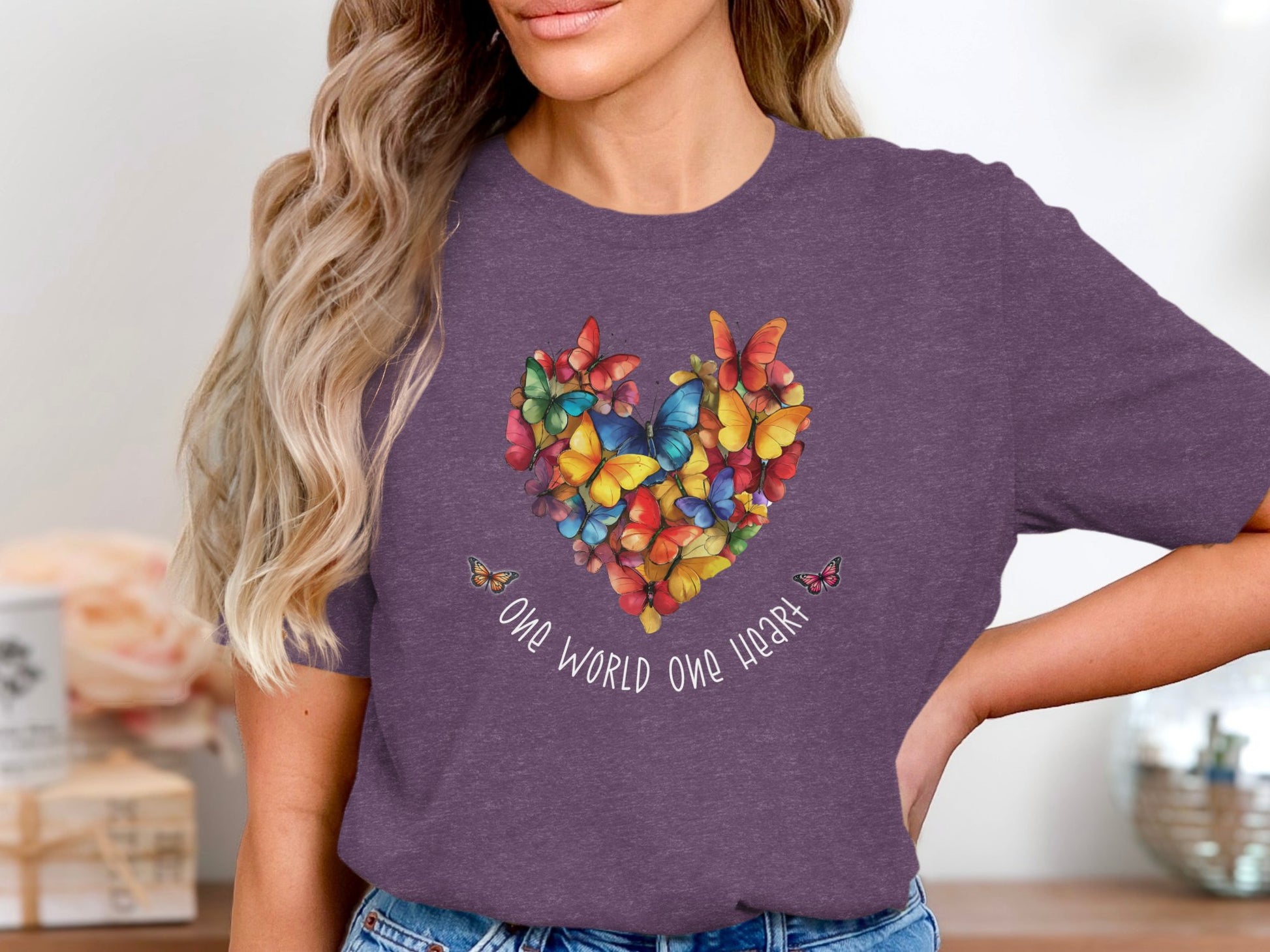 One World One Heart t-shirt with centred butterfly-formed heart graphic in cobalt, coral, yellow and green on chest.