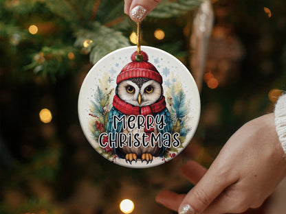 Round holiday ornament with woodland owl artwork, pine branches, red berries, snowflakes, and Merry Christmas text.
