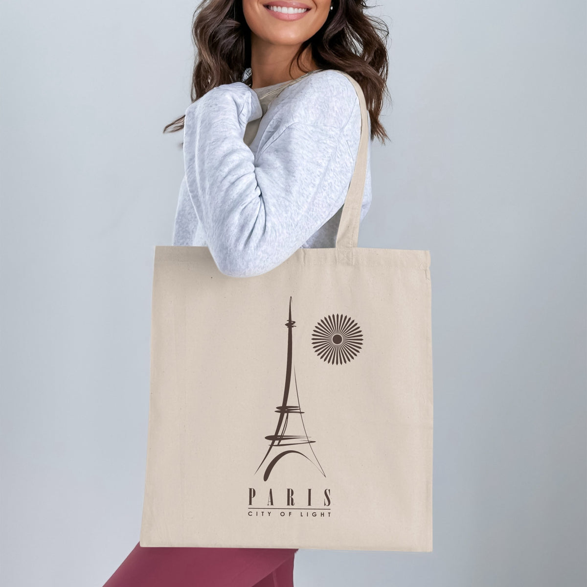 Paris City of Light Tote Bag worn over the shoulder, showing the full Eiffel Tower graphic and minimalist Paris typography beneath.