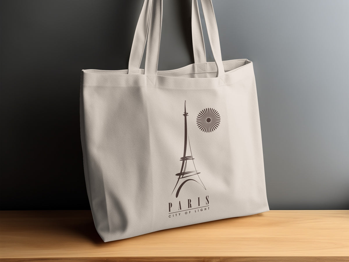 Paris City of Light canvas tote bag displayed on a sideboard, showing the dark brown Eiffel Tower artwork and spaced PARIS lettering beneath.