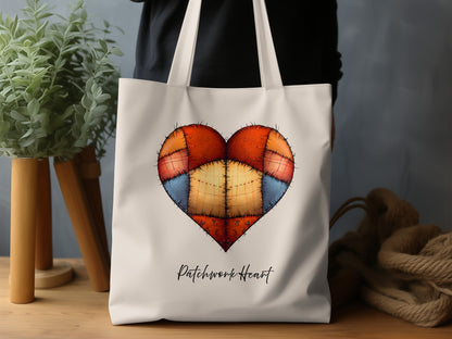 Natural Patchwork Heart canvas tote bag featuring a symmetrical rust-orange, peach, golden-yellow and blue heart with printed stitched detailing and black script.