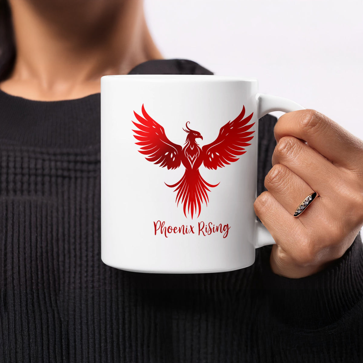 11oz Phoenix Rising Mug held in hand, showing the red phoenix with spread wings, raised head, curved tail feathers and red script lettering.