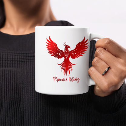 11oz Phoenix Rising Mug held in hand, showing the red phoenix with spread wings, raised head, curved tail feathers and red script lettering.